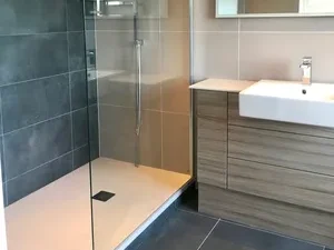 Modern bathroom featuring a glass shower, wall-mounted sink, and sleek cabinetry.