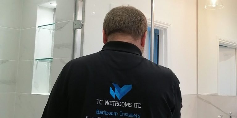 Person in a black shirt with a blue logo, viewed from behind in a modern interior space.